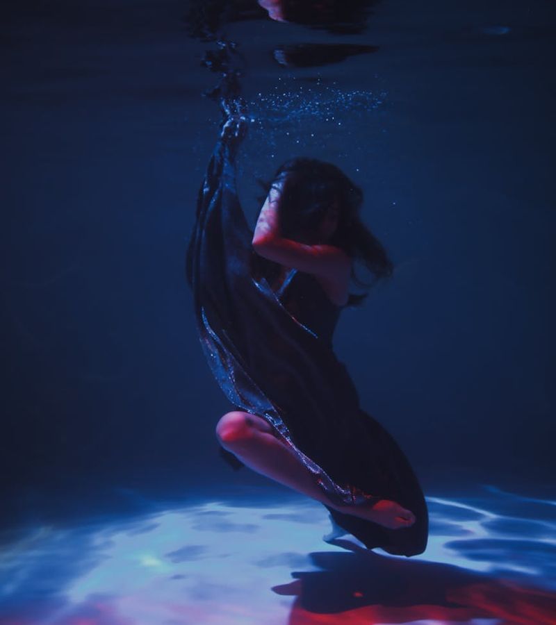 Woman performing a fluid cardio movement in a minimalist dark room.